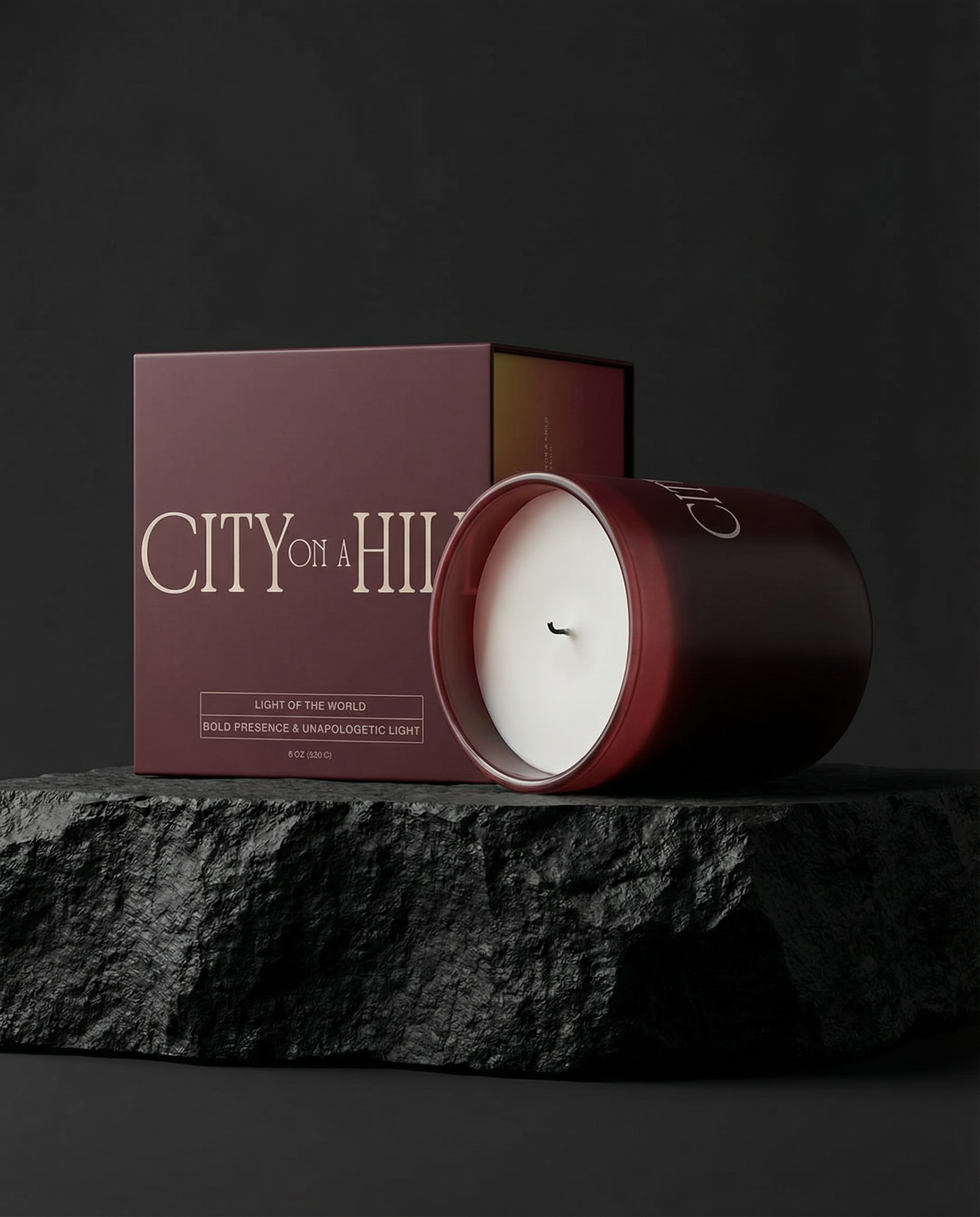 Fragrance to Fire candle on a dark surface, accompanied by a matching box labelled 'City on a Hill'. Light of the World