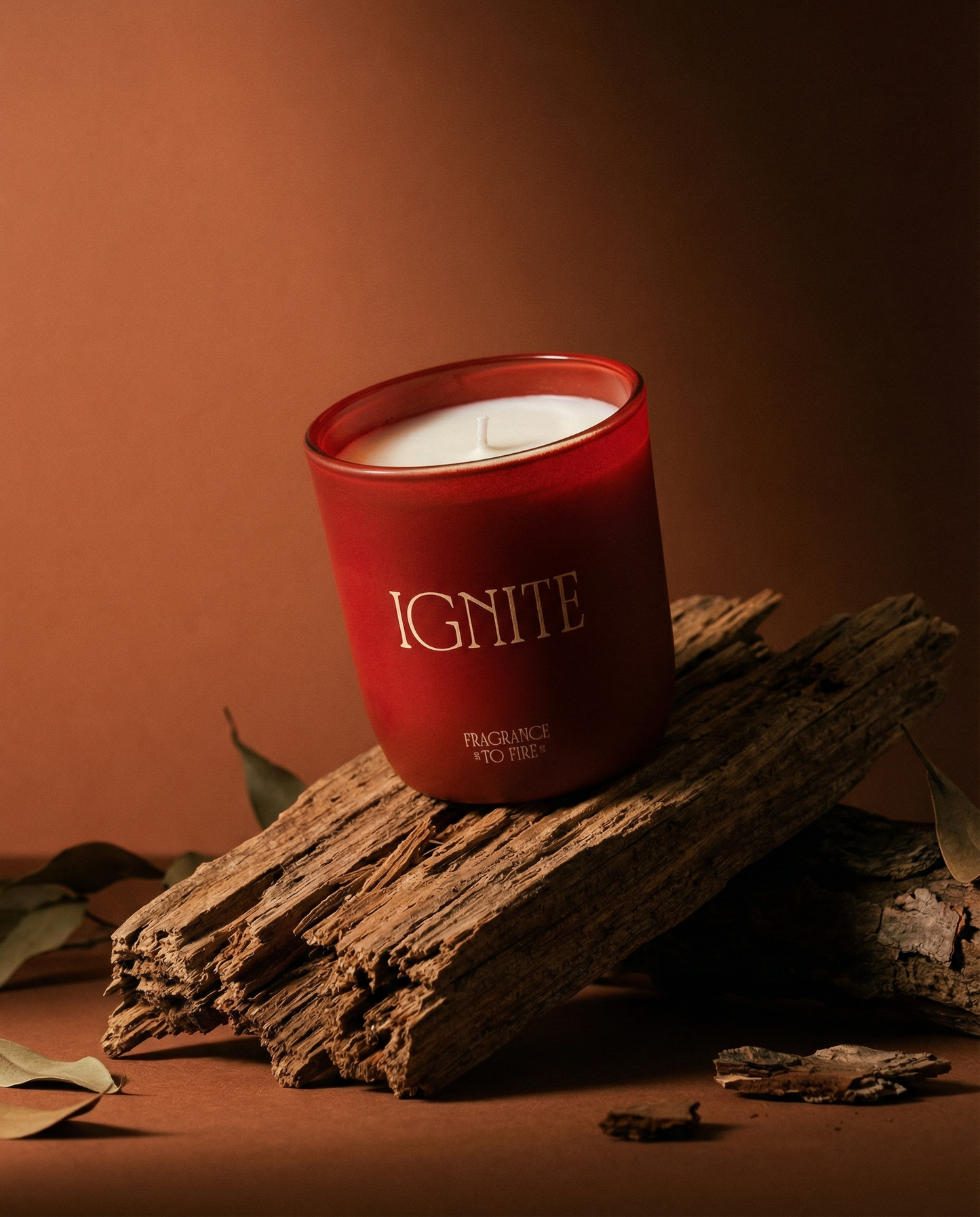 Red Ignite soy candle burning on a coaster, bold faith-inspired home fragrance with saffron scent. Fan into flame